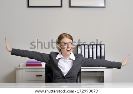 flying behind desk. Red haired female office worker flying behind her desk.