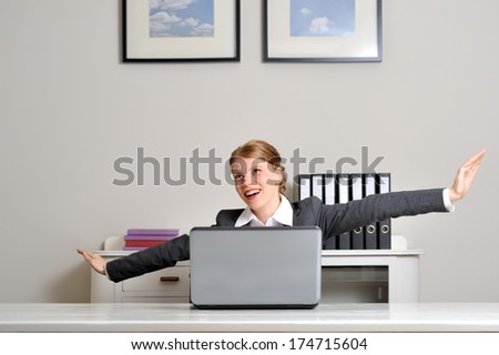 Red haired business woman flying behind her desk and laptop at the office. Looks like she\'s going to take off, playing an airplane.