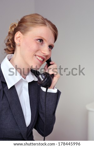 Red haired business woman on the landline vintage phone in a cheerful mood.