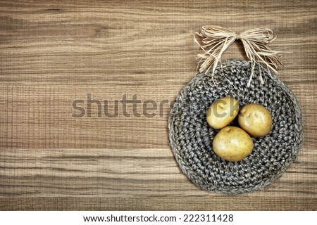 Beautiful decoration with fresh potatoes on linen doily. Image of natural materials. Eco style. Sweet composition with bow-knot on raw wooden background.