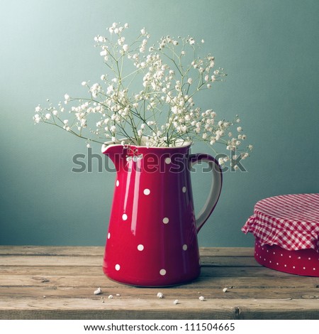Beautiful flowers in red jug on wooden table