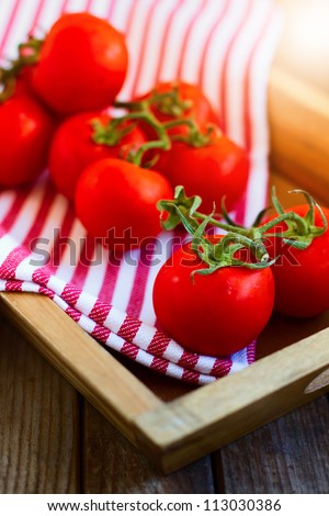 Fresh tomatoes in wooden tray on wooden tabletop