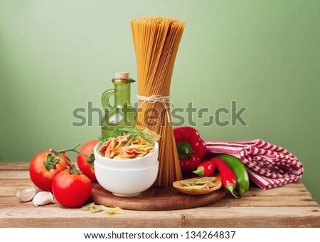 Still life with whole wheat pasta on wooden table over green background