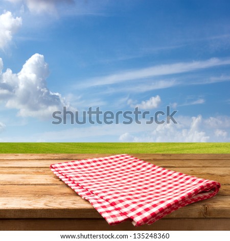Empty table with tablecloth over beautiful meadow and blue sky