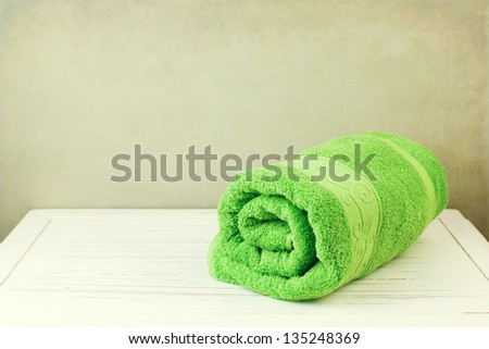 Fresh clean towel on white wooden table over grunge background