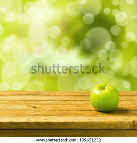 Green apple on wooden vintage table over bokeh background