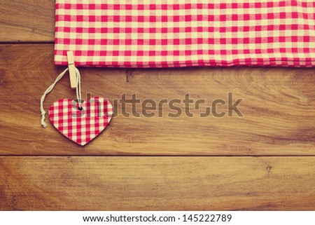 Retro toned background with checked tablecloth and heart shape on wooden board