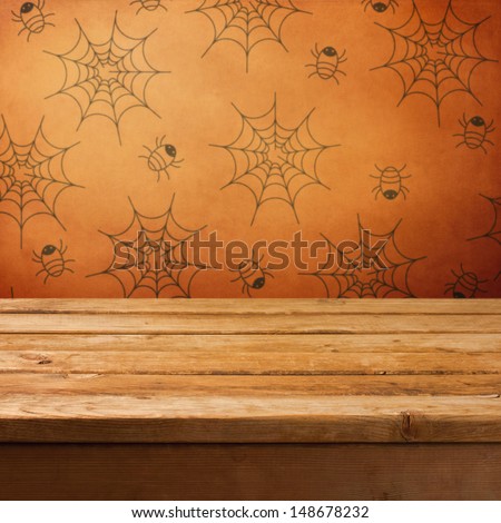Halloween holiday background with empty wooden table and wallpaper with spiders