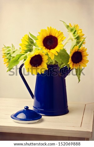 Sunflower bouquet in blue jug on wooden white table