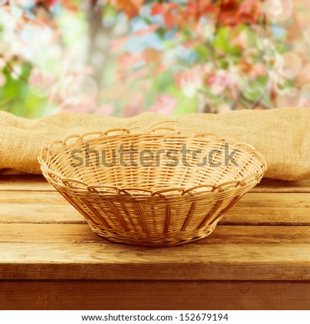 Empty basket on wooden table over bokeh autumn background