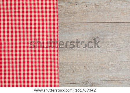 Wooden table covered with red checked tablecloth. View from the top.