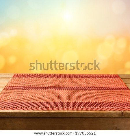 Bamboo tablecloth on wooden table over sunset bokeh  background. Ready for product display montage