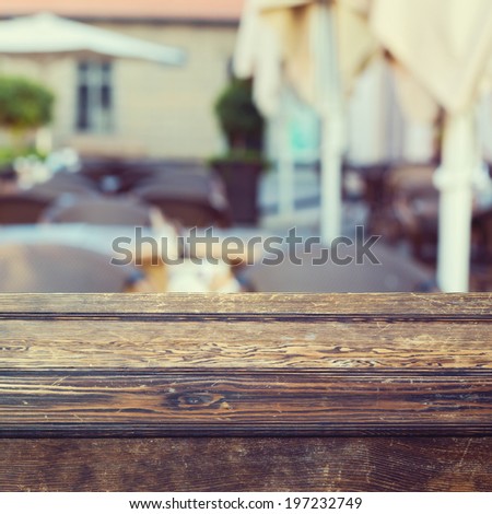 Wooden table over outdoor restaurant blur background