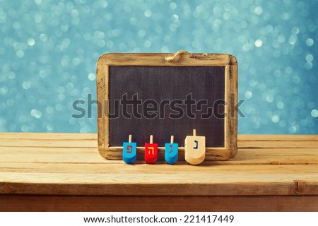 Jewish Holiday Hanukkah background with wooden dreidel spinning top and chalkboard over blue bokeh lights