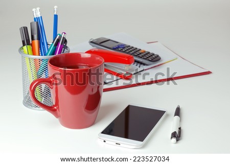 Mobile phone and office items on white tabletop. Business concept