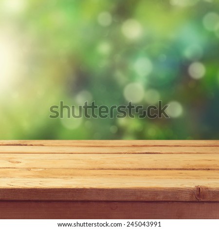 Wooden deck table with garden bokeh background. Ready for product display montage.