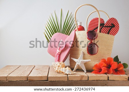 Summer beach bag and hibiscus flowers on wooden table. Summer holiday vacation concept. View from above