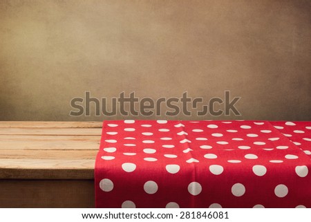 Empty wooden deck table with polka dots tablecloth over grunge background