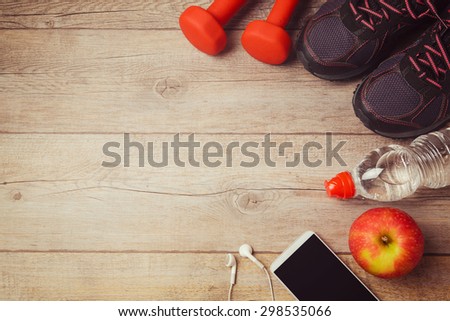 Fitness background with bottle of water, dumbbells and athletic shoes. View from above