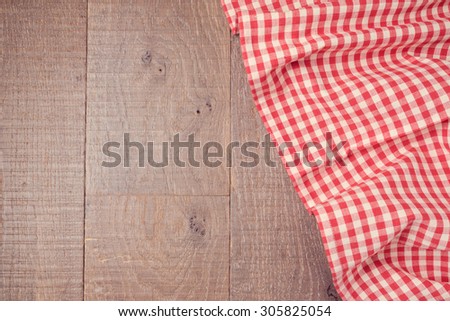 Wooden board background with red checked tablecloth. View from above