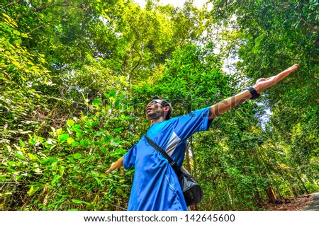 Enjoying the nature. Young man arms raised enjoying the fresh air in green forest.