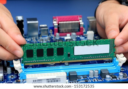 Technician\'s hands installing user memory on a computer main-board