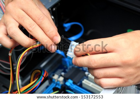 Closeup of a technician\'s hands wiring a computer mainboard