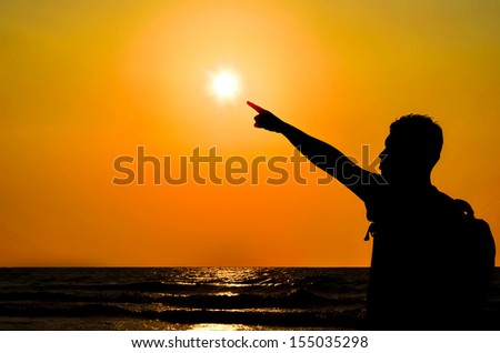 Silhouette of a man pointing towards the sun