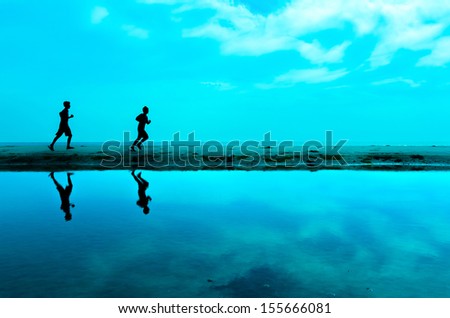 Silhouette of two man running at the beach