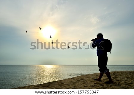 Photographer silhouette shooting near the beach when sun rising
