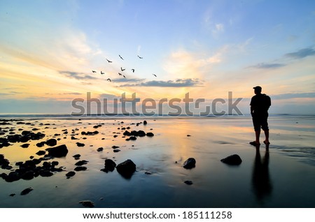 Silhouette of a photographer looking to the birds flying when sun rising up