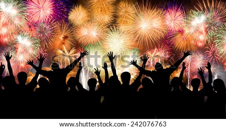 Group of people enjoying spectacular fireworks show in a carnival or holiday. People in silhouette