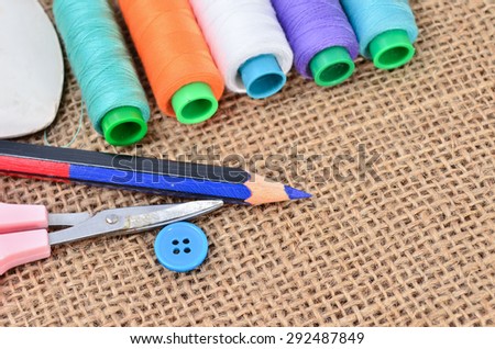 Sewing kit. Scissors, bobbins with thread and needles on the old fabric