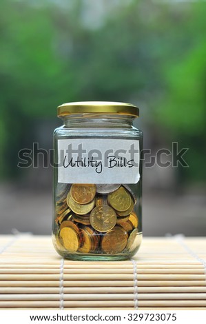 Coins in bottle with label Utility Bills - financial concept