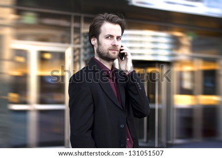 Forty years old businessman standing outside modern office building talking on a mobile phone