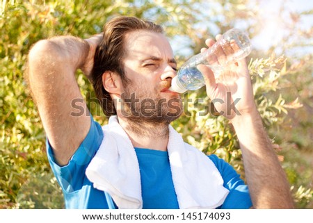 Forty years old caucasian active man drinking water and having a rest after workout during sunny summer day