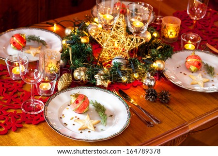 Christmas eve dinner party table setting with lights, gold glittering decorations and elegant white plates