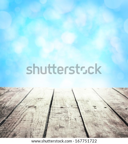 Winter rustic template background with text space. Old vintage planked wood table in perspective on blue abstract bokeh.