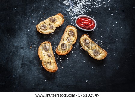 Baked cheese bruschetta toast on black table. Bar appetiser - background with free text space.