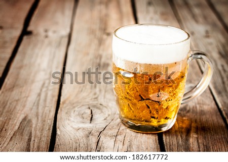 Beer mug on rustic vintage planked wood table. Background layout with free text space.