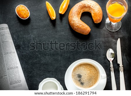 Continental breakfast on black chalkboard - bar menu. Coffee, orange juice, crescent roll and jam from above. Background layout with free text space.