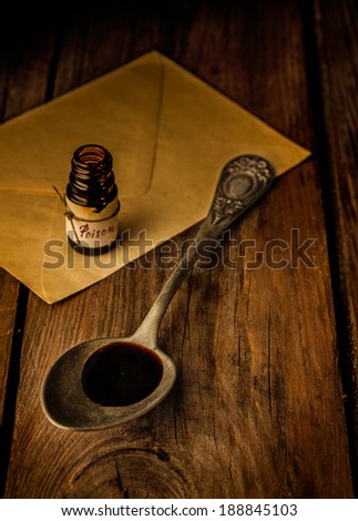 Vintage spoon, ancient poison bottle and a letter on rustic wood table. Dark, moody, retro still life.