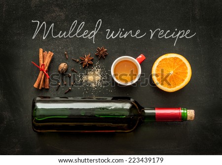 Mulled wine recipe ingredients on black chalkboard - christmas or winter warming drink. Bottle of wine, honey, orange, cinnamon sticks, anise, nutmeg, cloves and sugar from above.