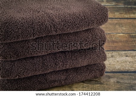 Stack of brown, organic cotton towels on a dark wooden background.