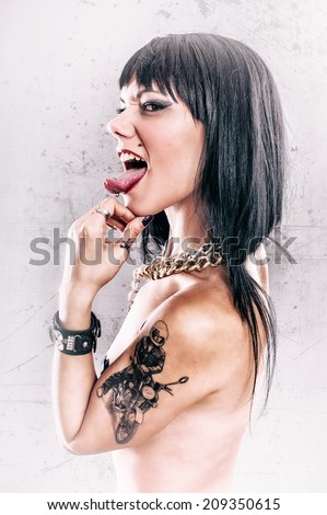 Grunge Tattoo Girl with Tongue Piercing. Aggressive and sexy tattoo lady with tongue piercing. Studio shoot.