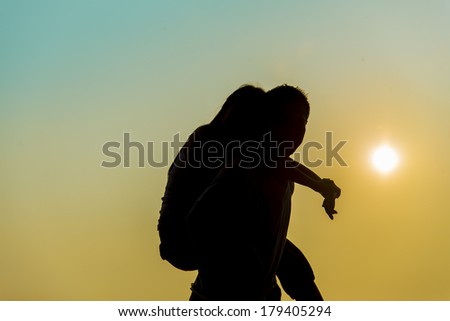Lovely Couple piggy back ride on sunset in Silhouette  scene