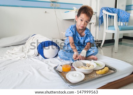 Asian patient boy with saline intravenous (iv) on hospital bed. Are eating .