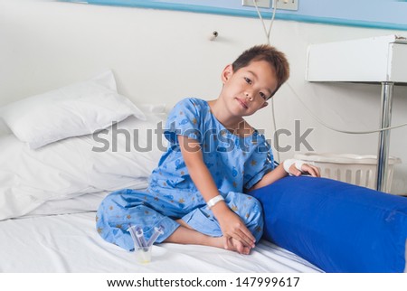 Asian patient boy with saline intravenous (iv) on hospital bed. Are using the tablet and eating medicines.