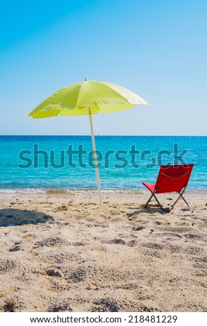 Yellow beach umbrella and lounge chair on a beach in Sardinia