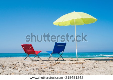 Yellow beach umbrella and two lounge chairs on a beach in Sardinia